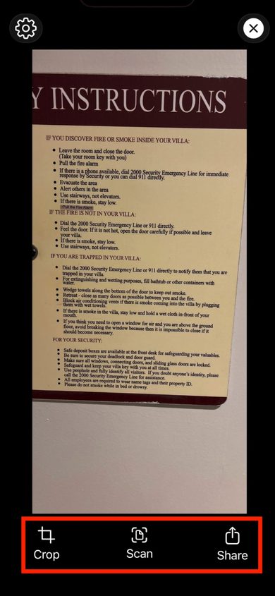 Sensory Reader camera view showing a hotel fire instructions document with Crop, Scan, and Share buttons at the bottom